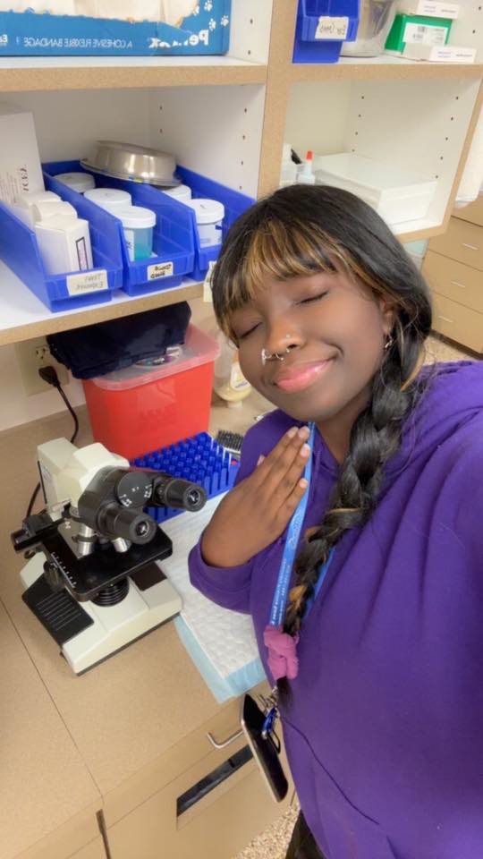 Alexandria Washington smiling beside a microscope in the clinic laboratory