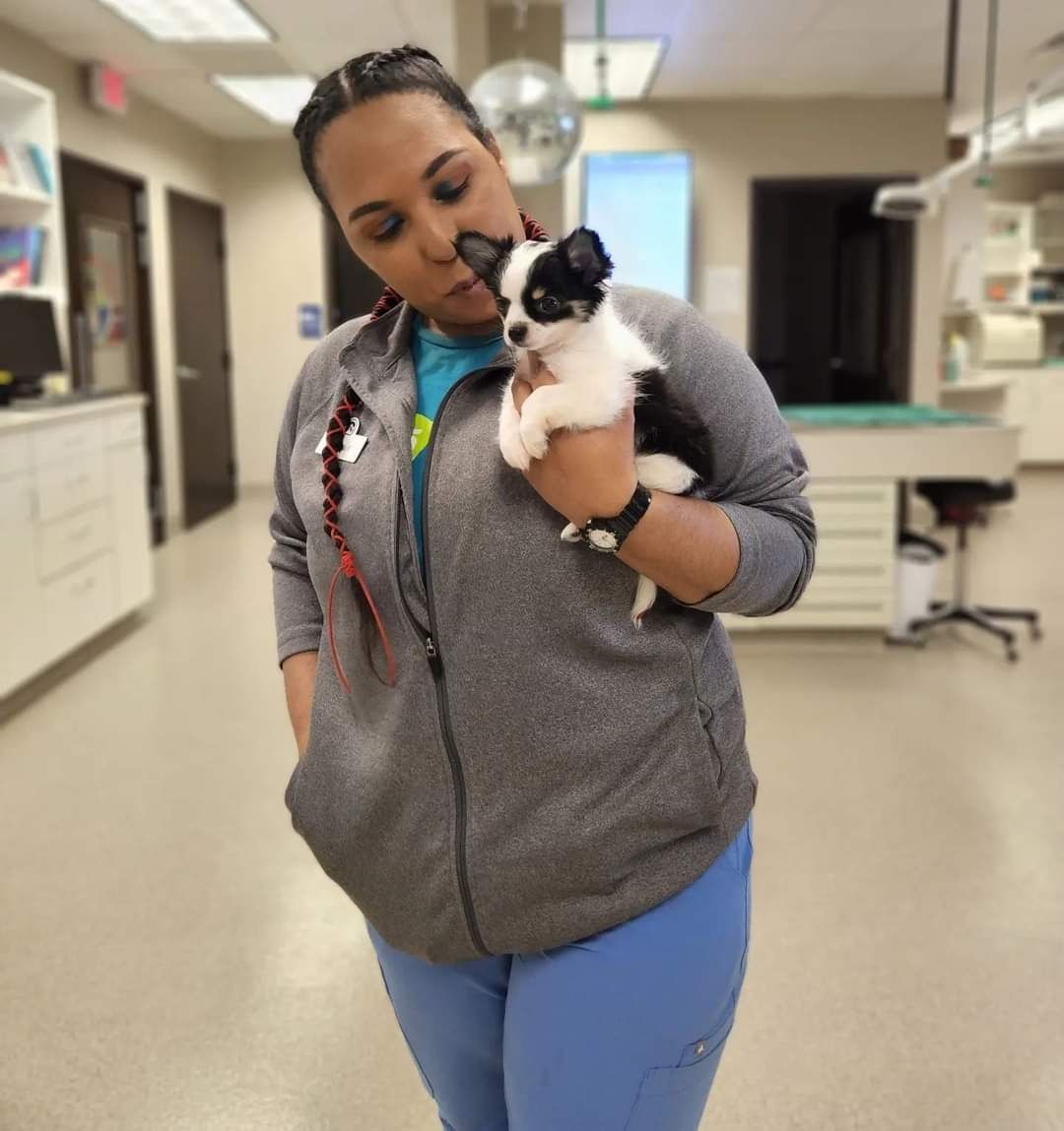 Dominique Pretty Birdsong holding a tiny black and white puppy close in the clinic