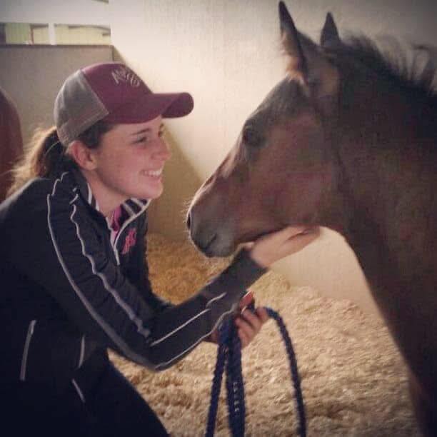 Kelsey Marriott face to face with a bay foal in a bedded stall